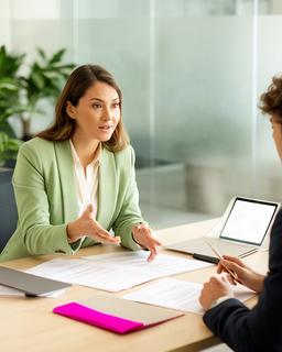 Abogada mercantil asesorando a una emprendedora ante una mesa con documentos de empresa